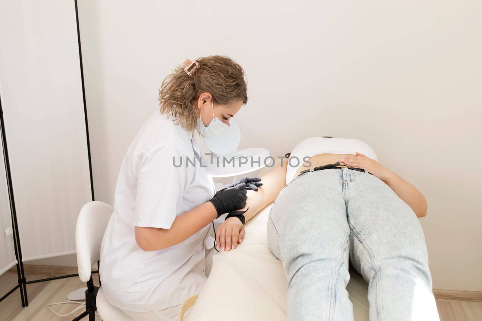 Female Specialist Doing Hair Removal Procedure With Electrolysis On Hand Of White Young Client, Electroepilation In Beauty Salon. Horizontal Plane. Authentic High quality photo