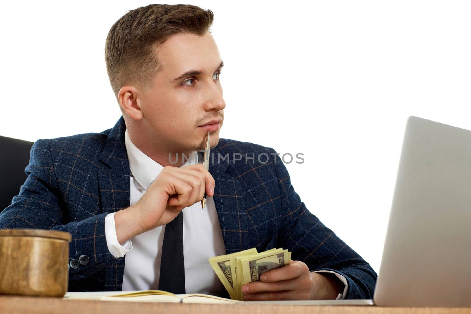 handsome businessman working on laptop and holding money while sitting on chair at desk.