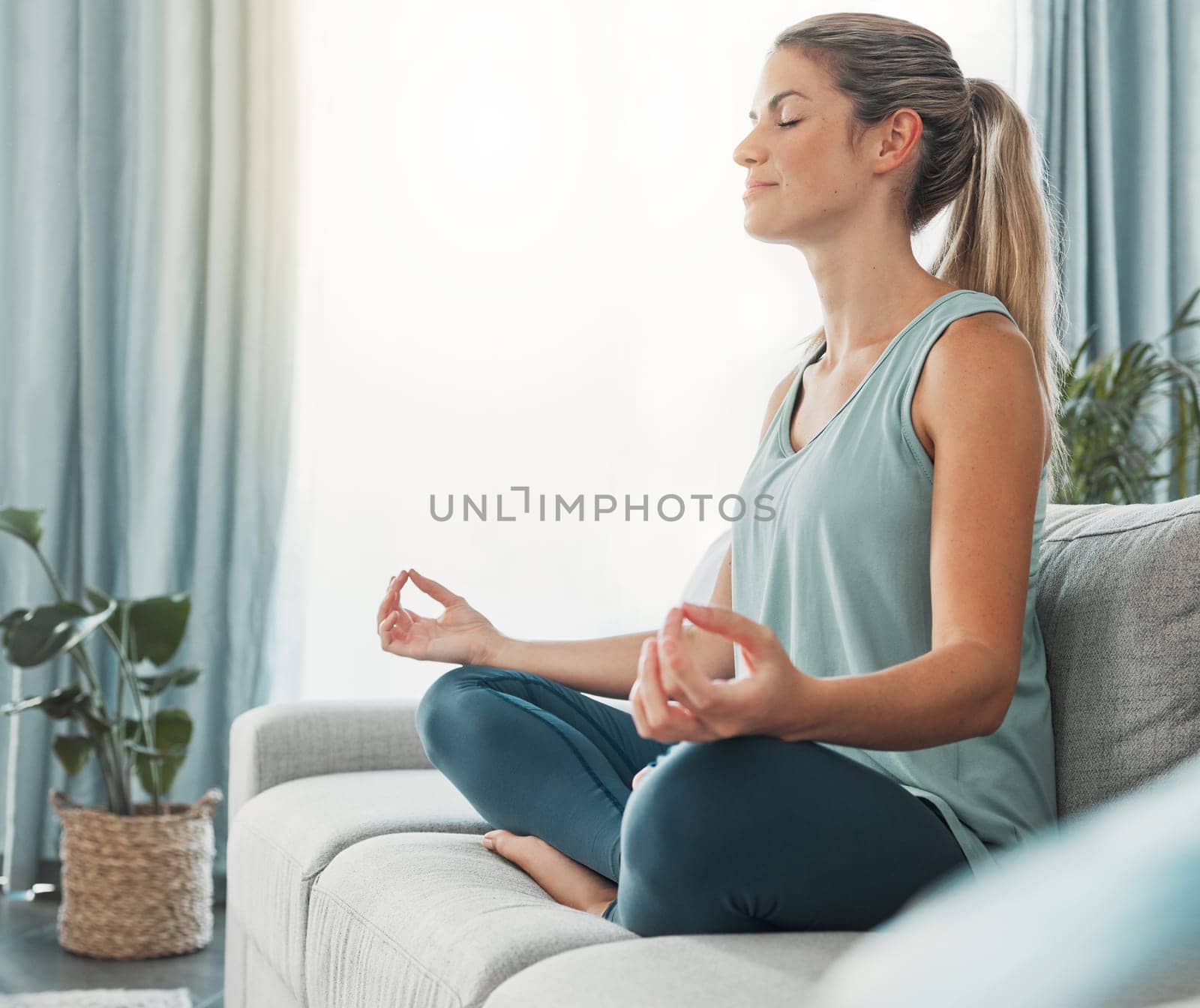 Meditation, yoga and woman doing exercise for fitness, health and peace while sitting in lotus on sofa in lounge at home. Russia female calm and zen during wellness, mindfulness or spiritual practice by YuriArcurs