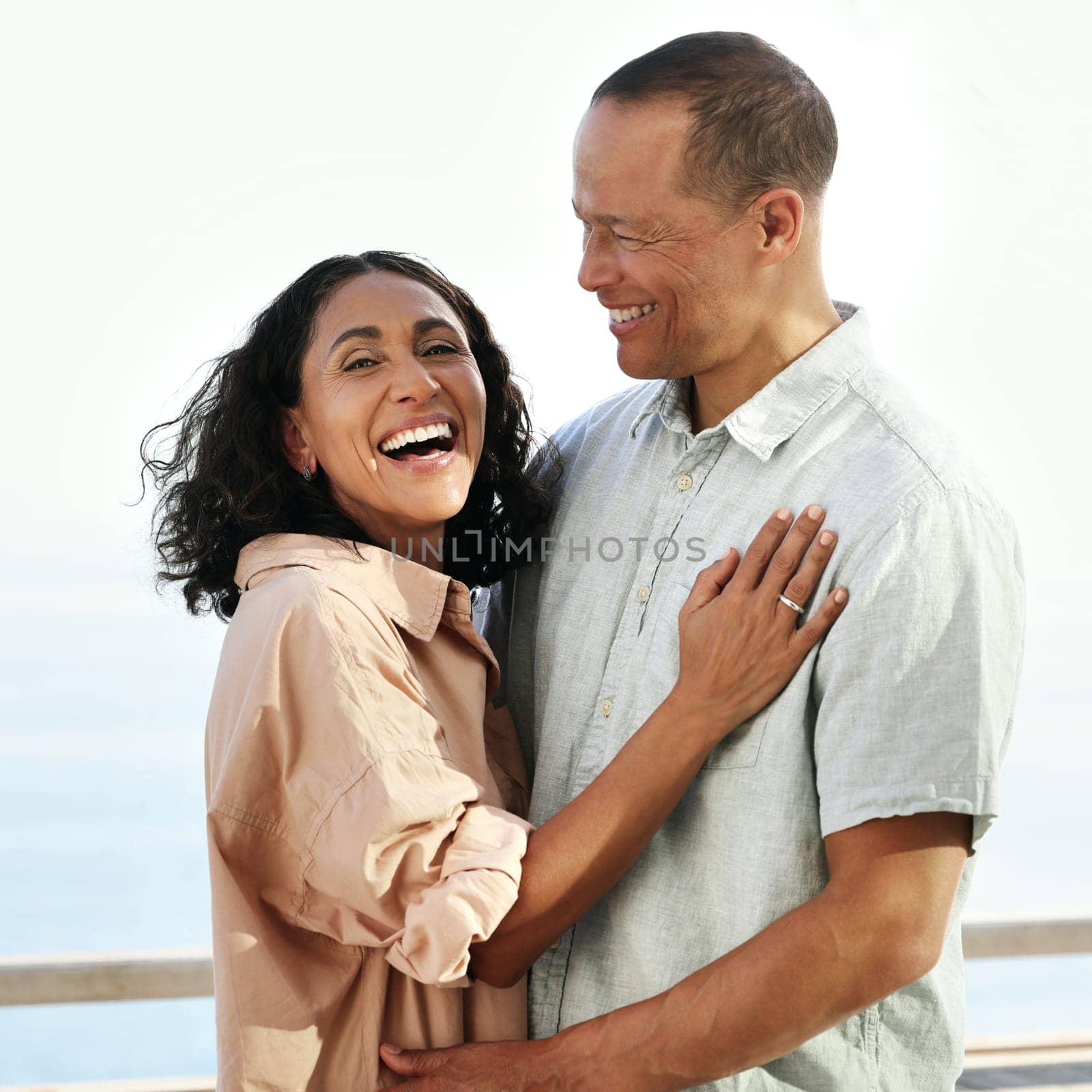 Portrait, laughing and senior couple by beach, hug and enjoying quality time on holiday or vacation. Love, comic and retired happy man and woman laugh at funny joke or comedy while having fun by sea. by YuriArcurs