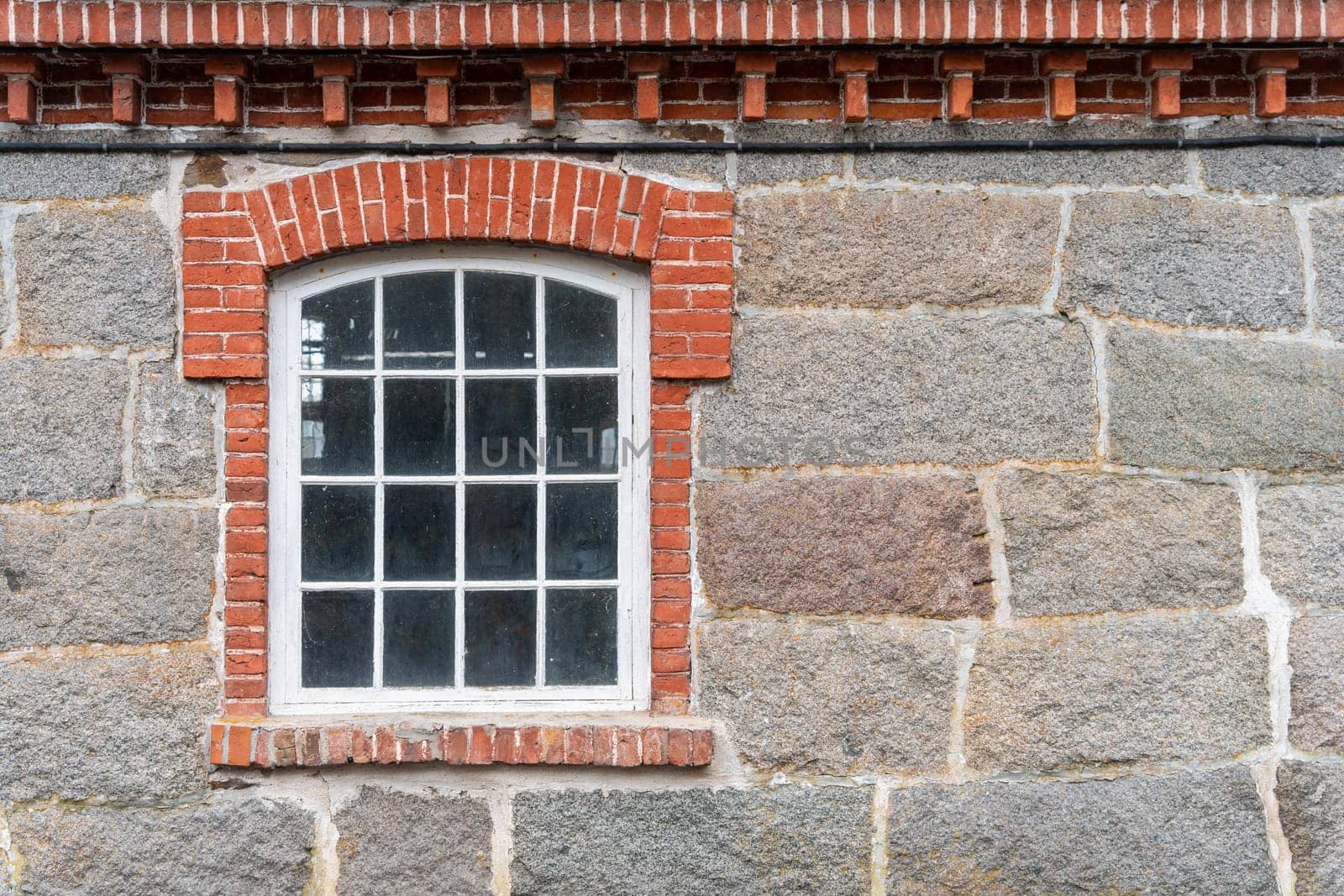 Photo of The window of the old mansion 19 century with grey stone wall.