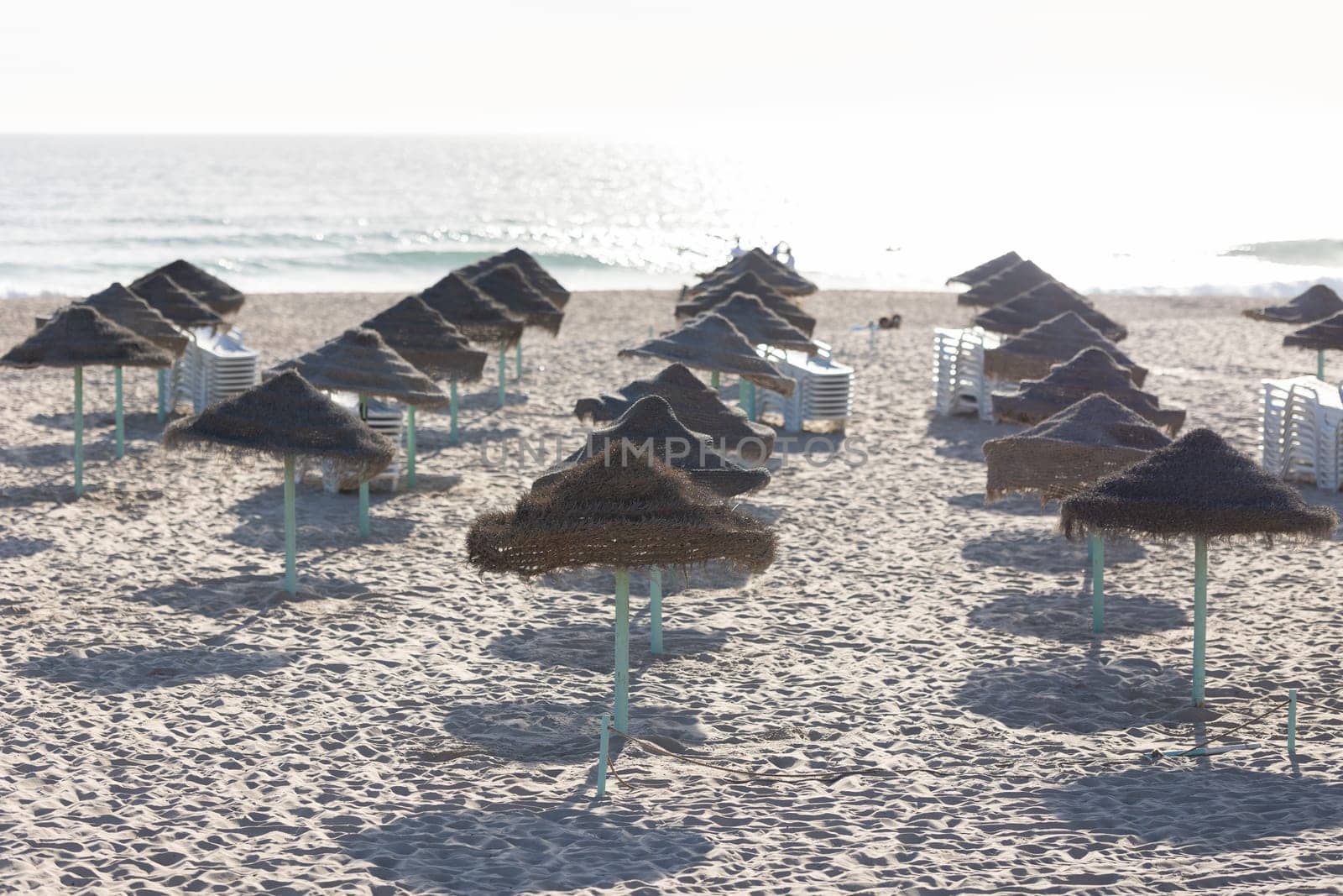 Straw umbrellas on the beach. Mid shot