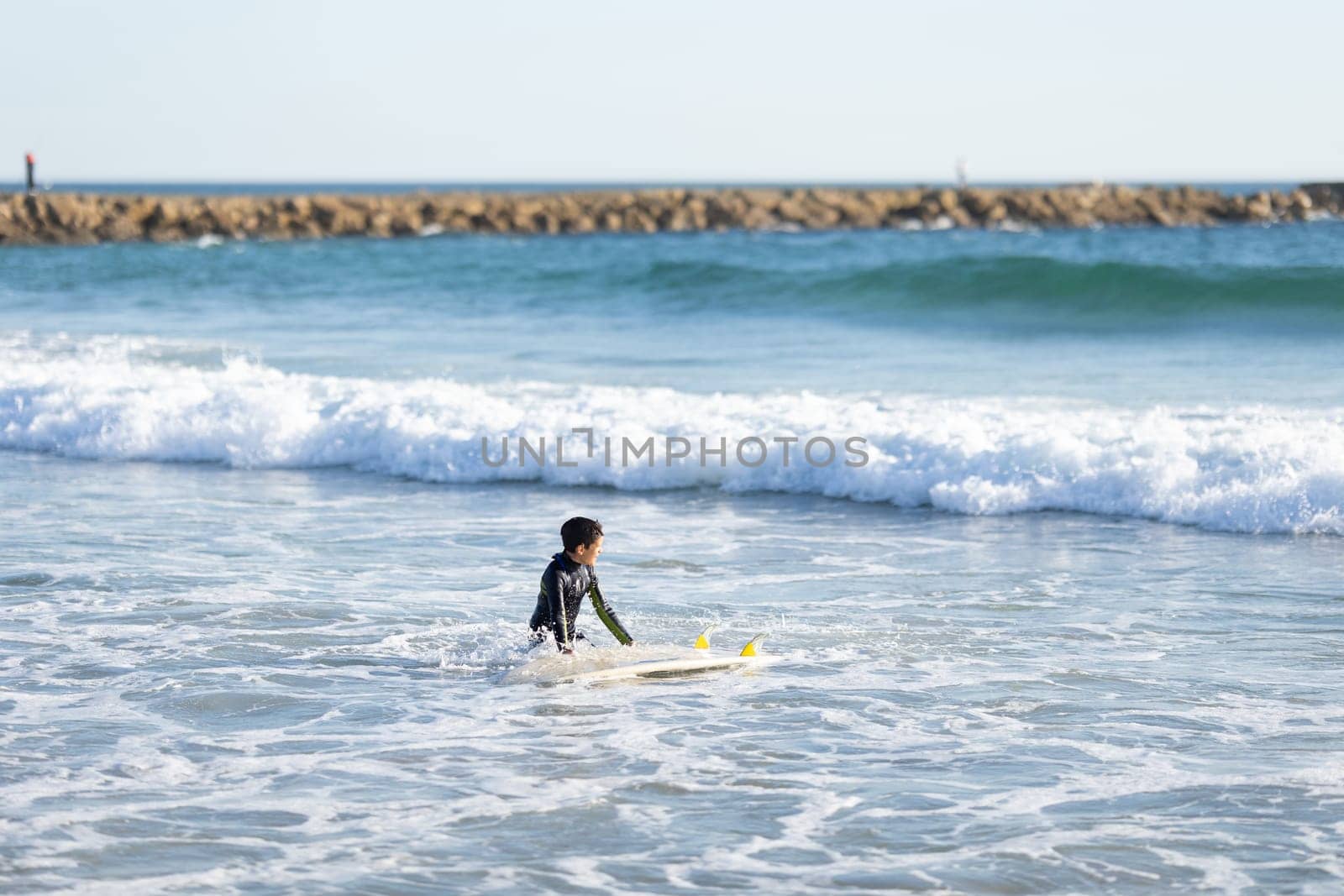 A little boy surfer in the sea. Mid shot