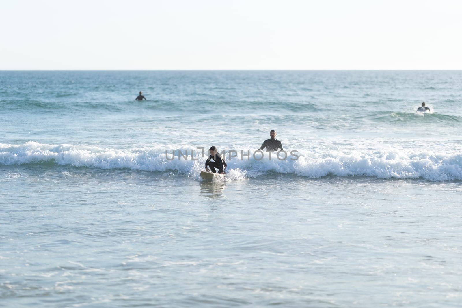 A family of surfers - father teaching his son how to serf. Mid shot