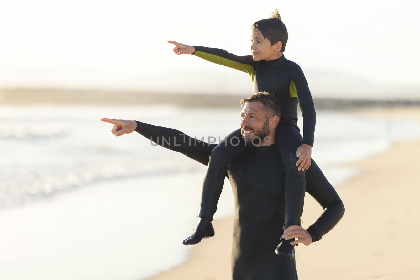Little son on the shoulders of his father pointing to the sea by Studia72