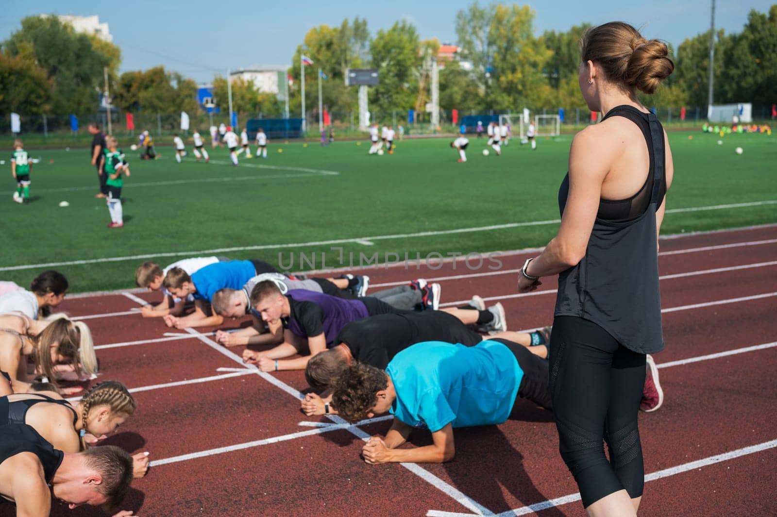 Female coach and group of children conducts a training session at the stadium. School gym trainings or athletics