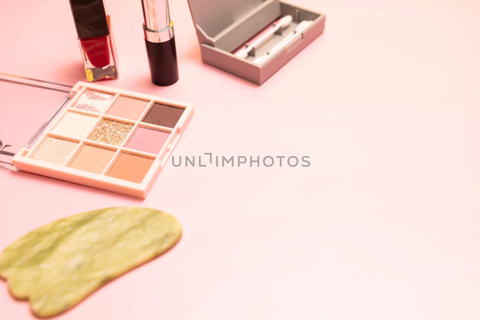 Mockup cosmetics, beauty and skin care products on pink background. Copyspace gua sha scraper, red lipstick, nail polish, eye shadow palette, reusable cotton buds Space for text, horizontal plane.