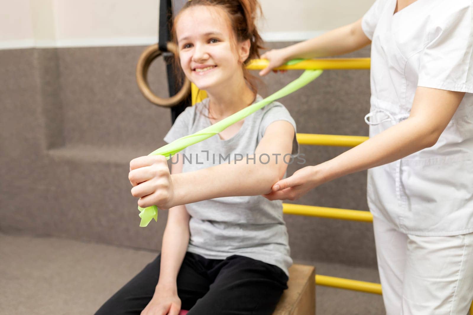 Happy Child With Disability Does Physical Exercises With Support Of Doctor In Rehabilitation Room. Kid With Special Needs. Rehabilitation. Cerebral Palsy. Motor Disorder. Horizontal plane