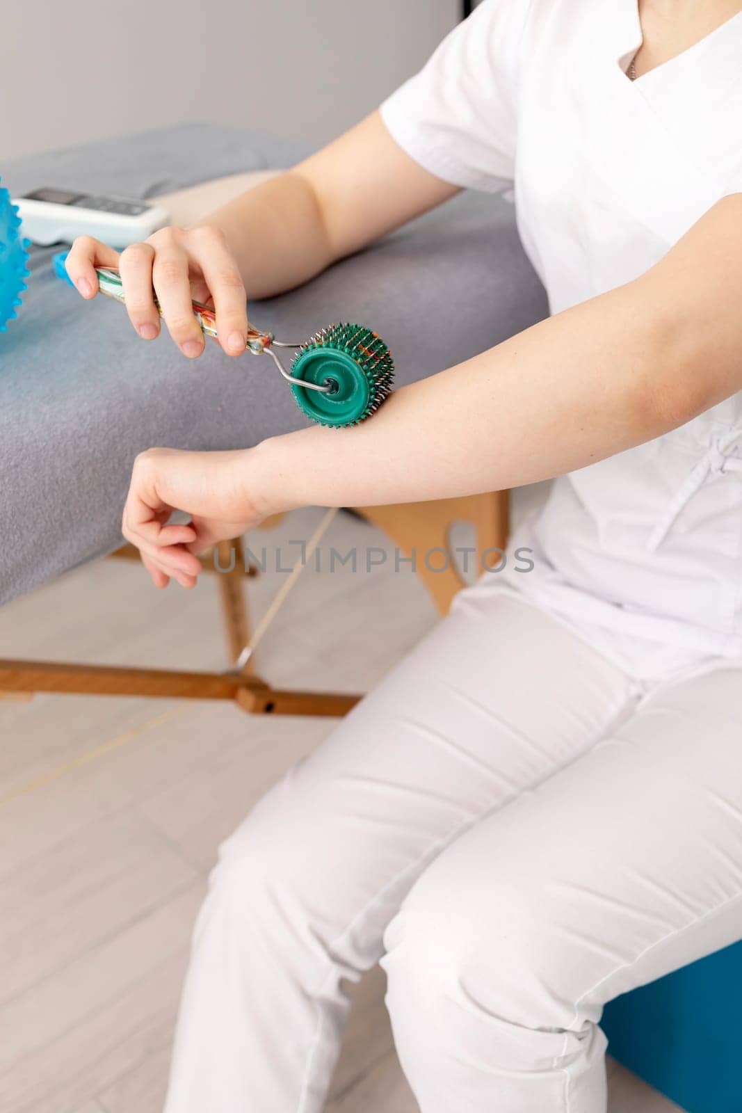 Closeup Rehabilitation Specialist, Physical Therapist Shows Rehab Tool Meso Roller With Titanium Needles On Hand, Massage Ball With Pimples in Therapeutic Room. Healthcare, Rehabilitation. Vertical.