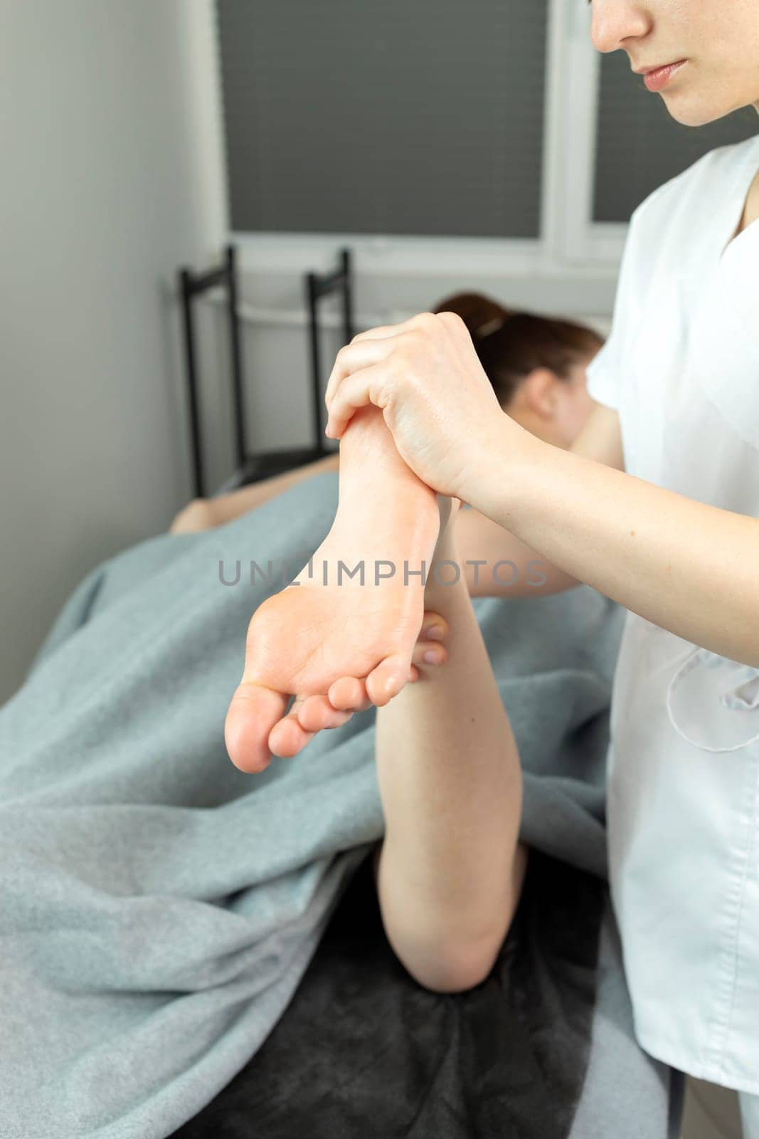 Rehabilitation Specialist, Physical Therapist Makes Foot Massage To Child With Cerebral Palsy, Scoliosis. Health Specialist, Rehabilitation. Vertical plane. High quality photo