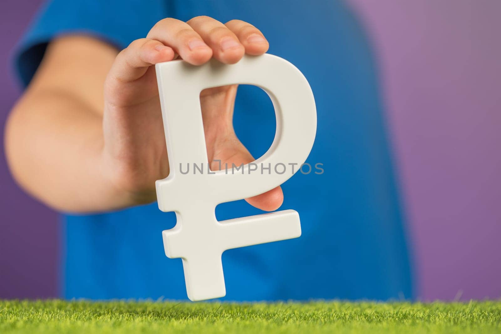 Ruble symbol in hands on a purple background. The concept of the growth or fall of the value of the ruble in the economy. Banner on financial topics. Recession and crisis in Russia. High quality photo