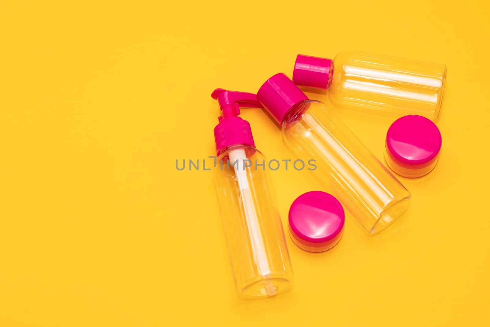 Top view travel bottle kit for liquids, cream. Toiletries Beauty Kit on yellow orange background. Airplane approved luggage reusable container size. Summer time, vacation. Horizontal. Copy space.