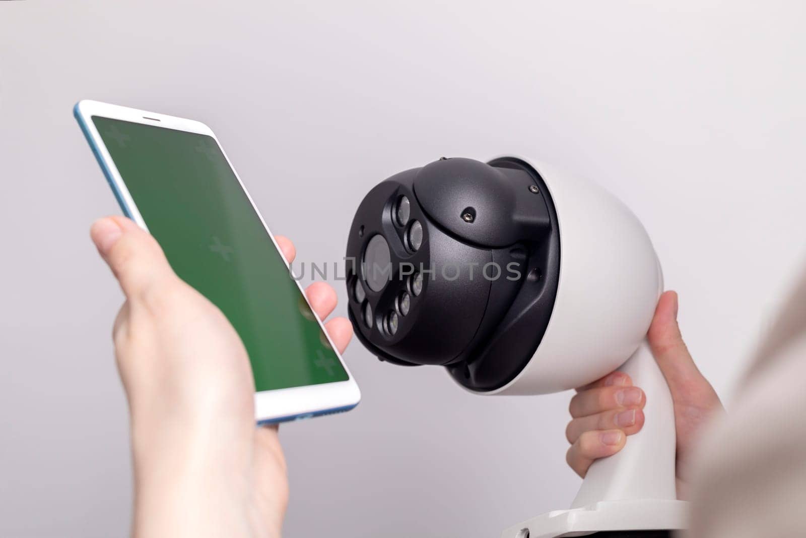 Surveillance IP Video Wireless Camera, Chroma Key Green Screen of Smartphone On Gray Background. Security Equipment For Smart Home with Online Remote App Monitoring, Control. Horizontal plane.