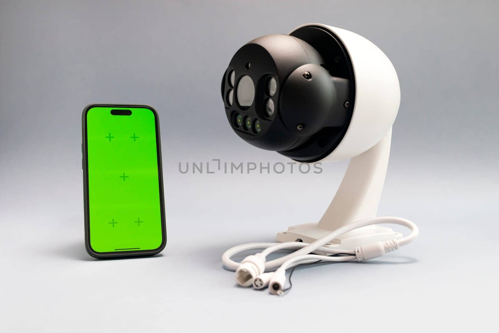 Surveillance IP Wireless Camera, Chroma Key Green Screen of Smartphone On Gray Background. Security Equipment For Smart Home with Online Remote App Monitoring, Control. Horizontal plane, mockup.