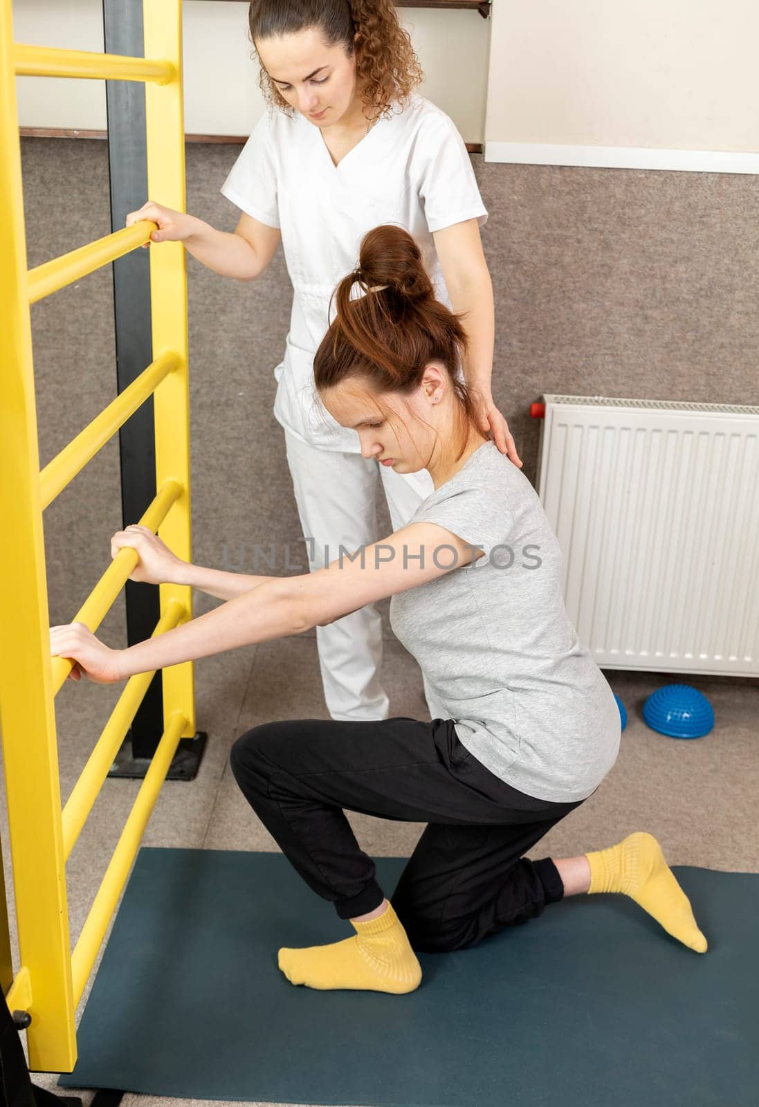 Disabled Child With Physician Does Physical Exercises In Gym. Kid With Special Needs. Rehabilitation. Cerebral Palsy. Motor Disorder. Vertical plane. High quality photo