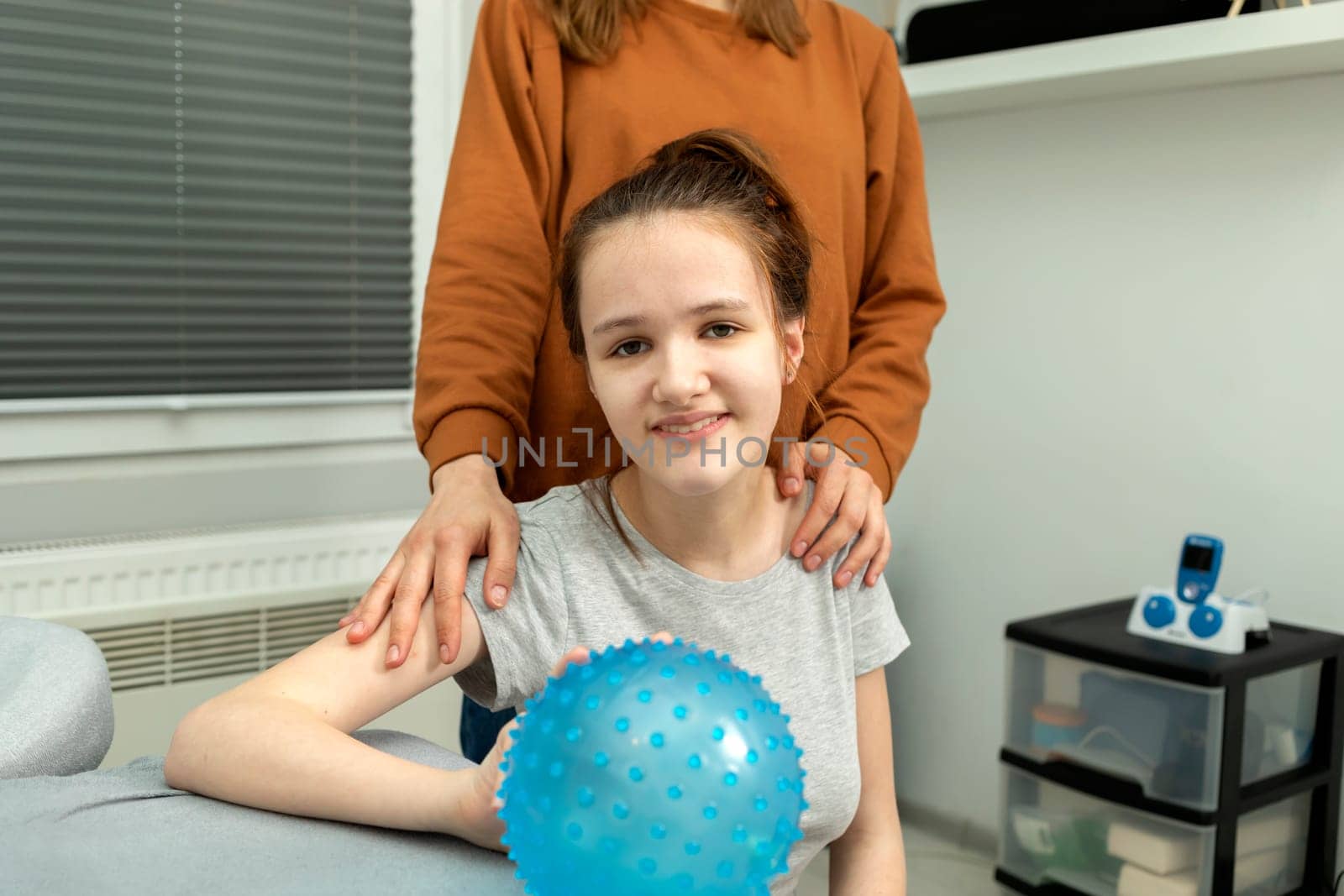 Portrait Of Pretty Smiling Teenage Girl With Disability With Mother Hugging Girl's Shoulders.Caring Loving Parent, Rehabilitation Cerebral Palsy. Balance And Posture Maintenance Horizontal plane
