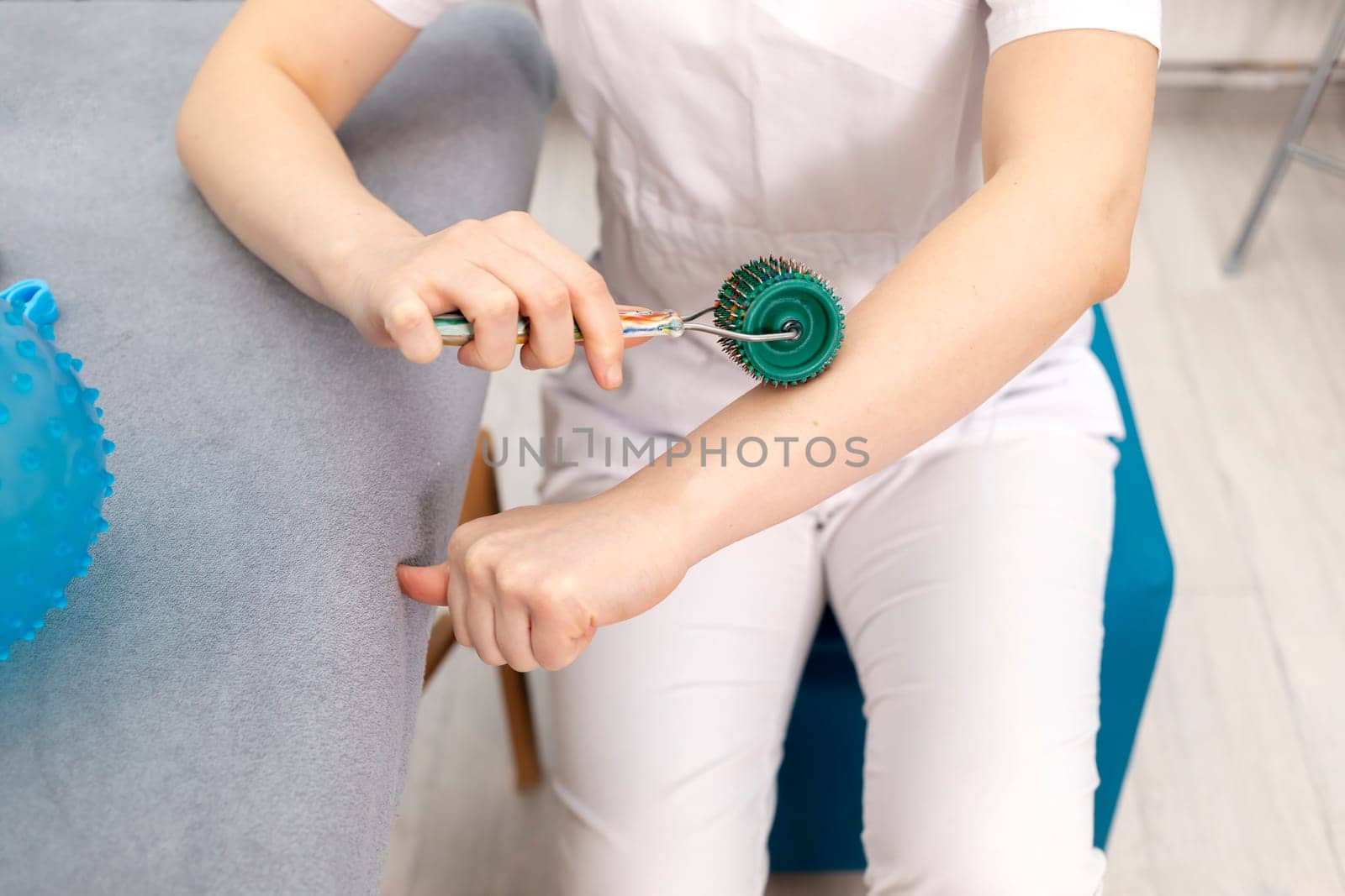 Rehabilitation Specialist, Physical Therapist Demonstrates Rehab Tool Meso Roller With Titanium Needles On Hand, Massage Ball With Pimples in Therapeutic Room. Healthcare, Rehabilitation. Horizontal.