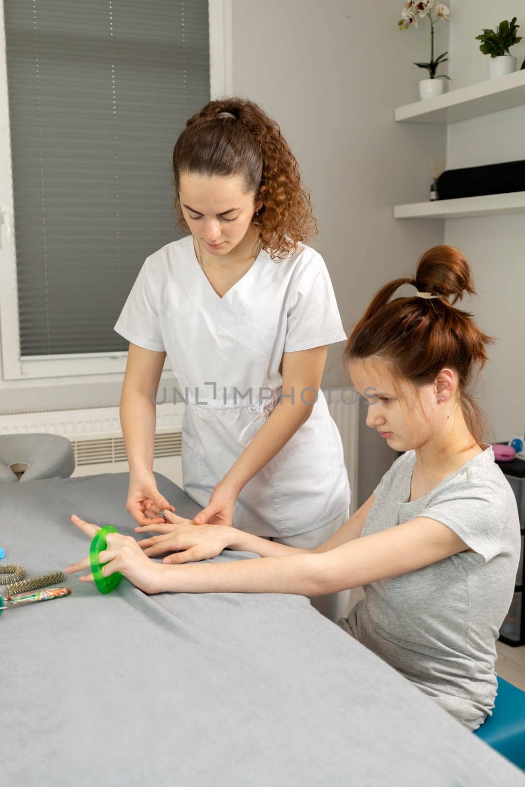 Doctor Neurologist Stretches Fingers Of Child with Disability. Physical Therapy Equipment, Cerebral Palsy, Athetosis. Health Specialist, Rehabilitation. Vertical plane by netatsi