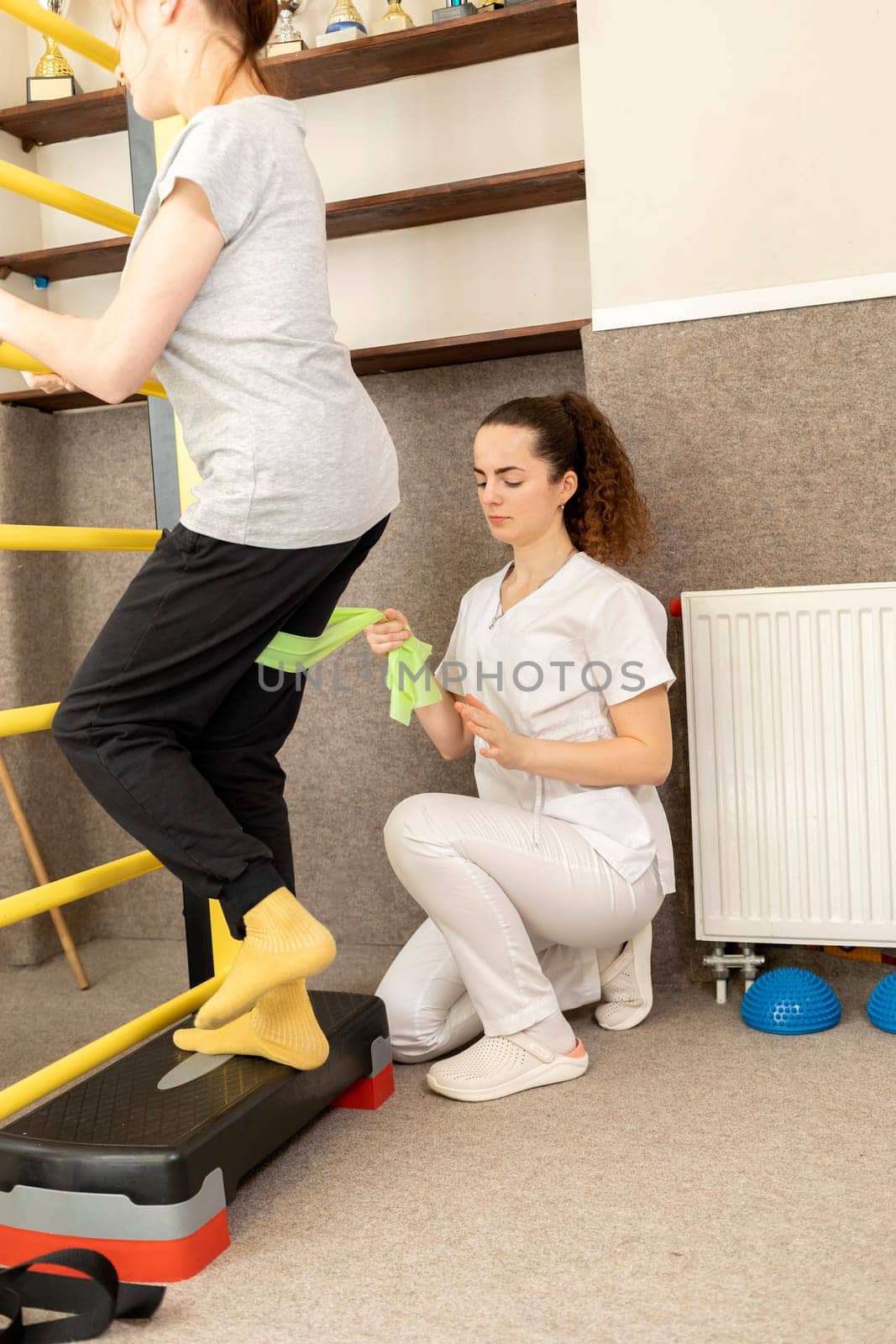 Disabled Child With Doctor Does Physical Exercises Near Gymnastic Wall In Rehabilitation Room. Kid With Special Needs. Rehabilitation. Cerebral Palsy. Motor Disorder. Vertical plane.High quality photo