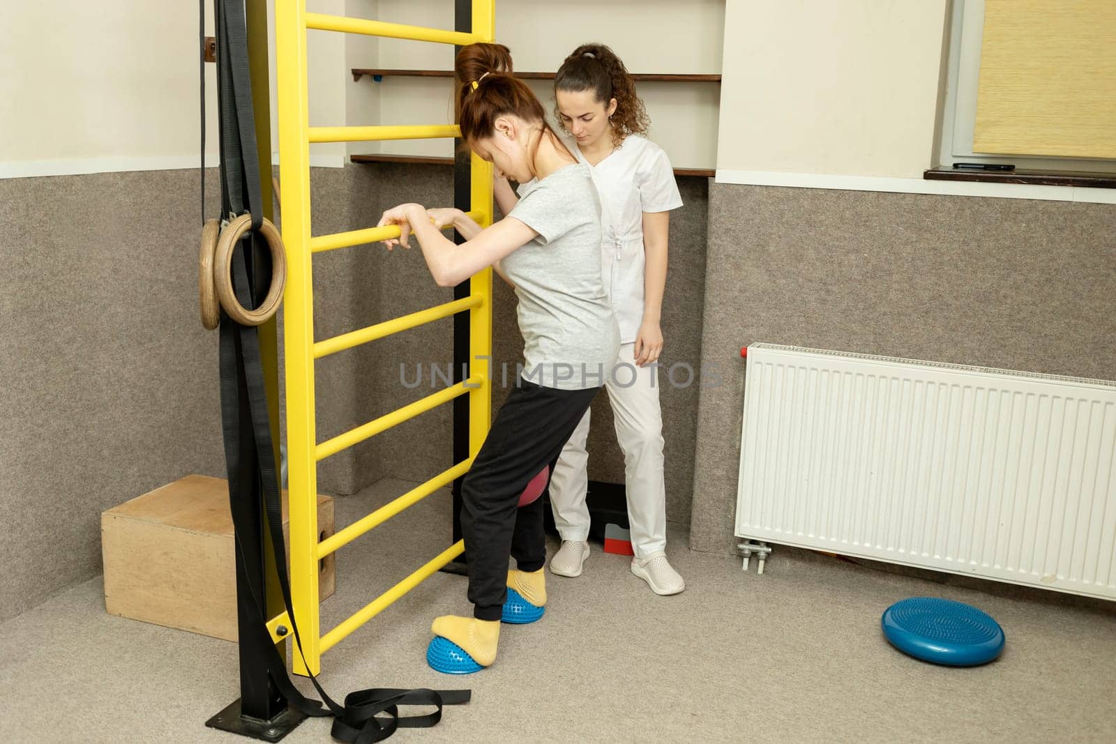 Disabled Teenage Girl With Doctor Does Physical Exercises In Rehabilitation Room. Child With Special Needs. Rehabilitation. Cerebral Palsy. Motor Disorder. Horizontal plane. High quality photo