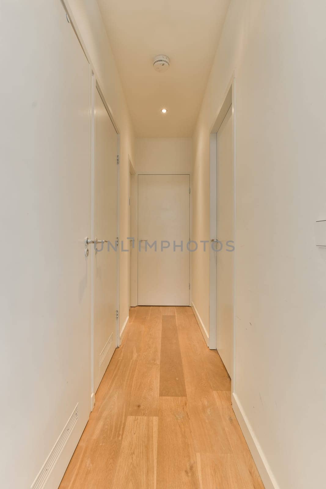 a hallway with wood floors and white walls and doors by casamedia
