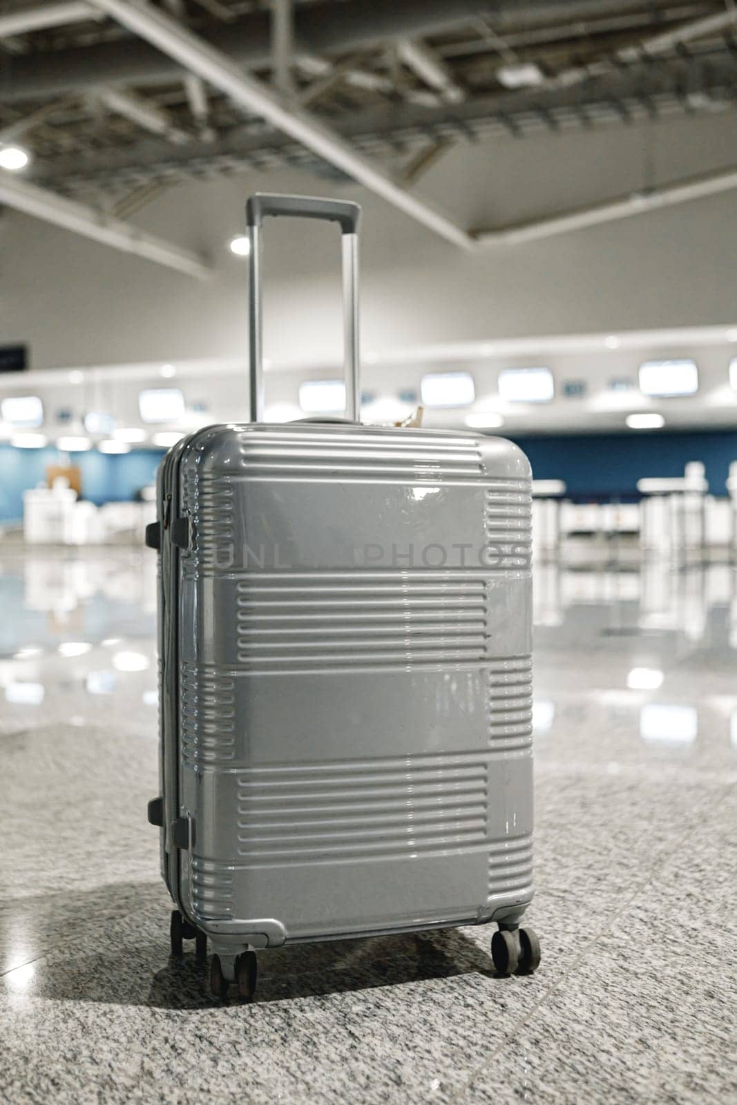 Gray travel suitcase in empty airport hall, close up