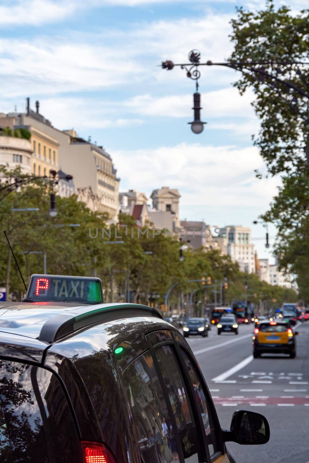 Taxi stands at the traffic light or waits for a passenger on the street of Barcelona. Selective focis. View to Passeig de Gracia.