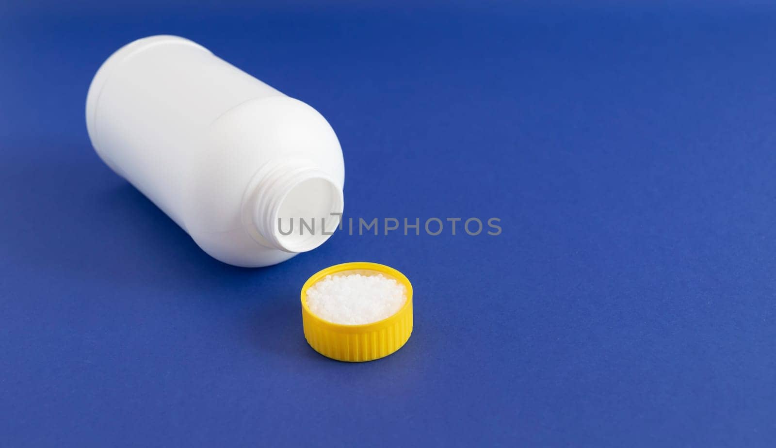 Plumber drain granules in Yellow Cap, White Plastic Bottle On Blue Purple Background, Copy Space. Super drain cleaner, Housework Help. High quality photo
