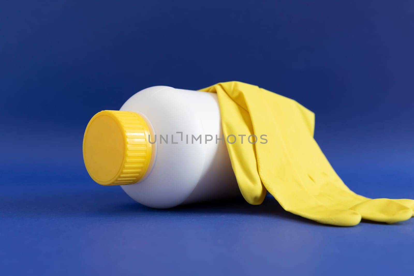 Pipe Unclogging Granules In Yellow Cap, White Plastic Bottle, Rubber Glove On Blue Purple Background. Super Drain Cleaner, Housework Help. Horizontal Plane, Closeup. High quality photo