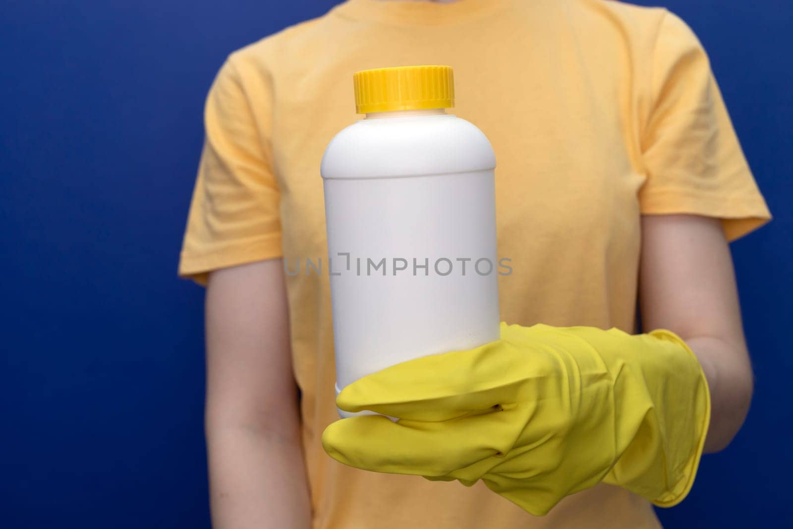 Woman In Yellow Gloves Holds White Bottle With Pipe Cleaner Granules. Removal Of Blockage In Sink, Shower With Special Chemicals. Cleaning Clog In Kitchen, Bathroom. Blue On Background, Horizontal.