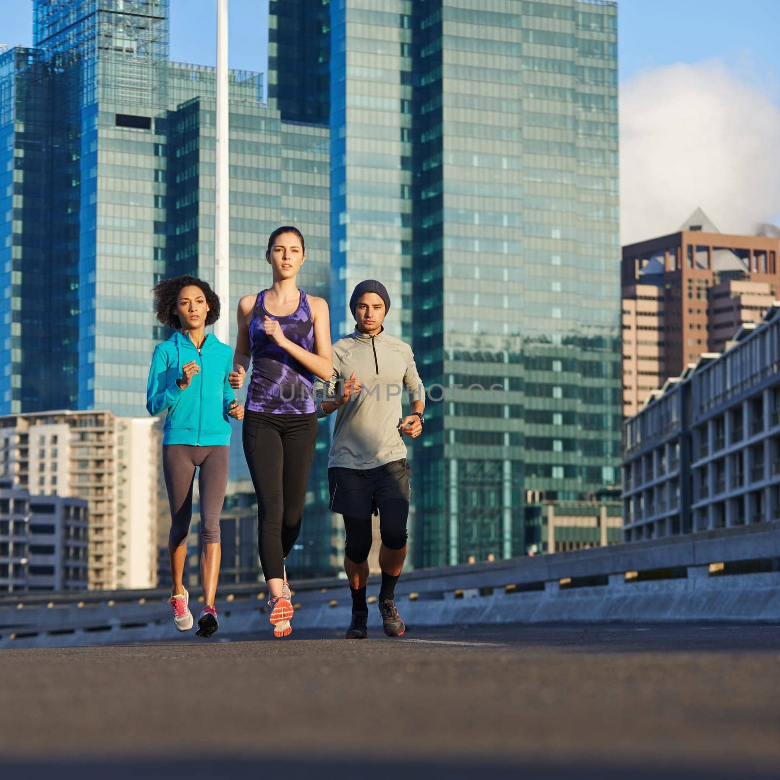 Were almost there...three young joggers out for a run in the city streets. by YuriArcurs