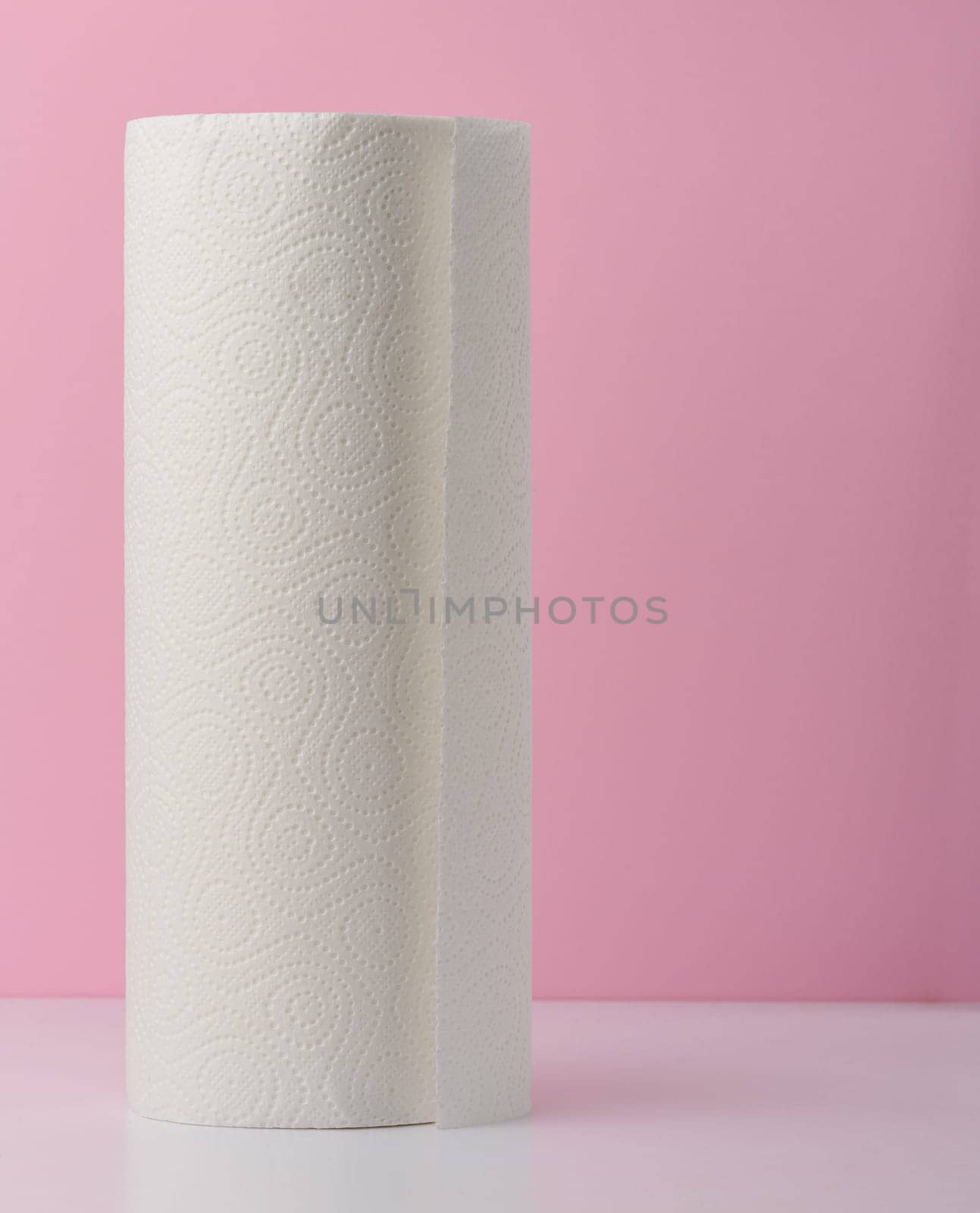 Roll of white kitchen towels on a pink background