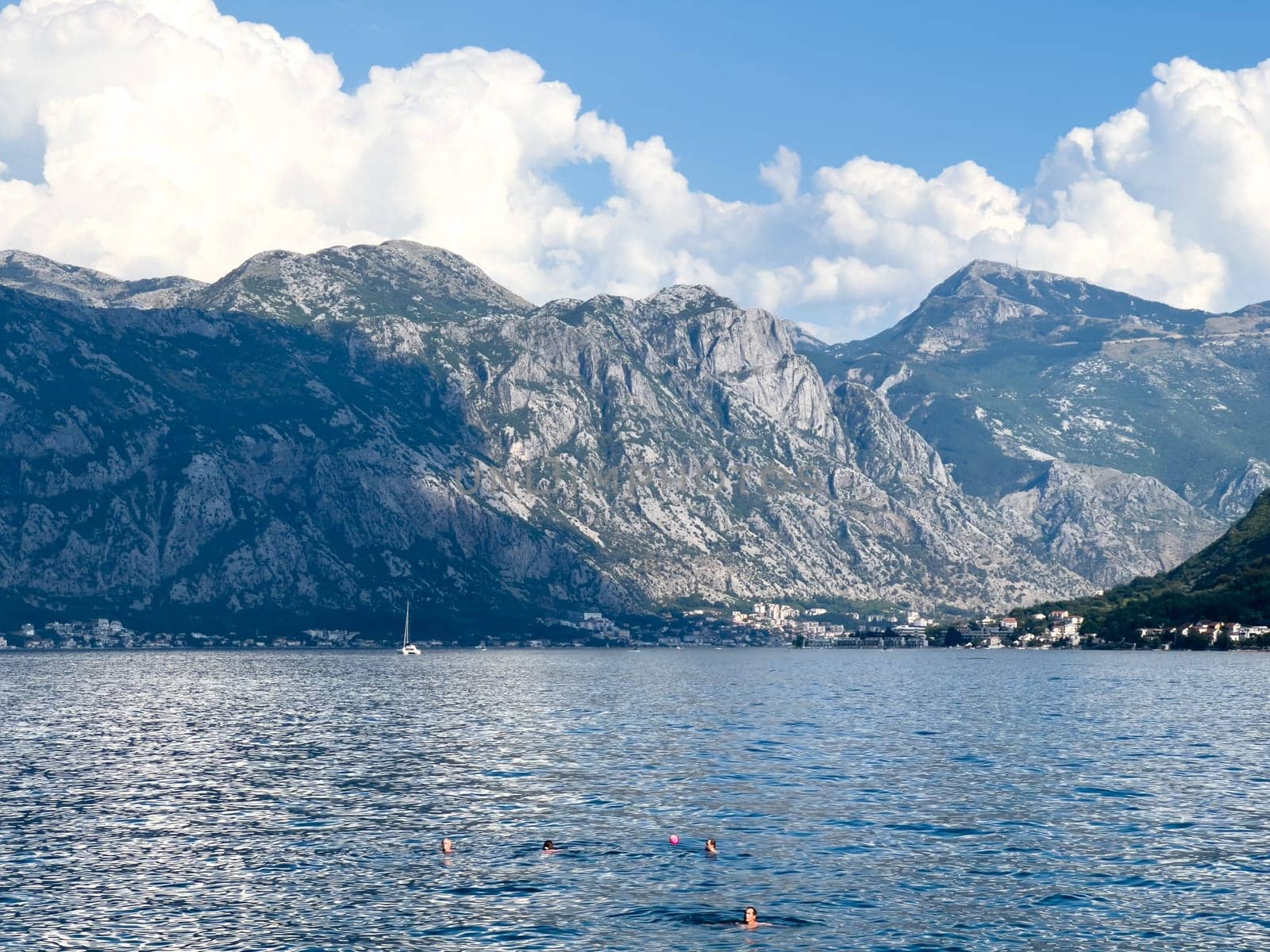 People swim in the bay against the backdrop of a high mountain range. High quality photo