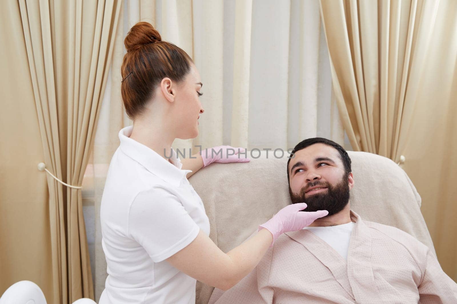 Beautician talking with young man in cosmetology cabinet