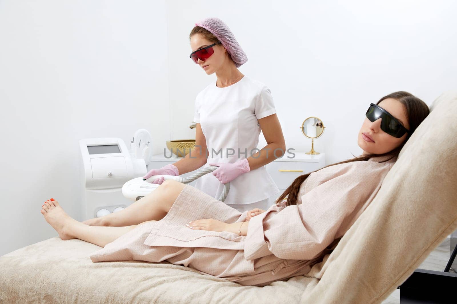 Woman receiving laser hair removal epilation on legs in a beauty salon by Mariakray