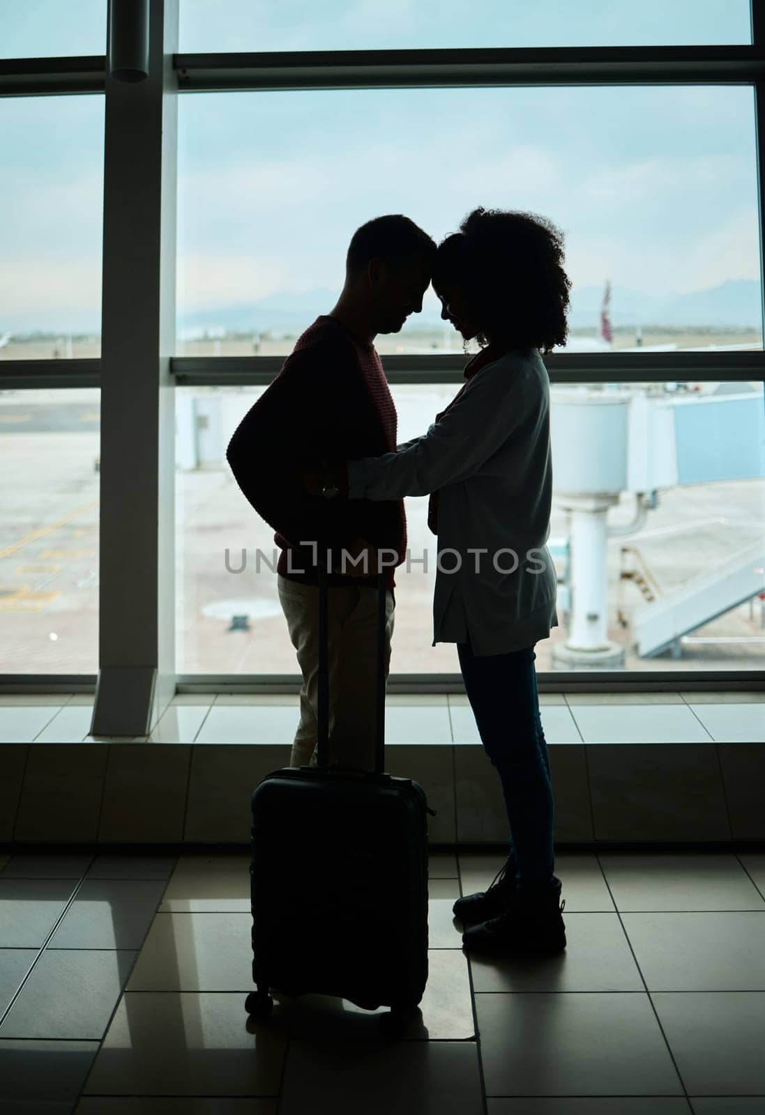 Silhouette, travel and love with couple in airport and hug for departure, flight and say goodbye. Shadow, holiday and sad man and woman leave in embrace by window for journey, international by YuriArcurs