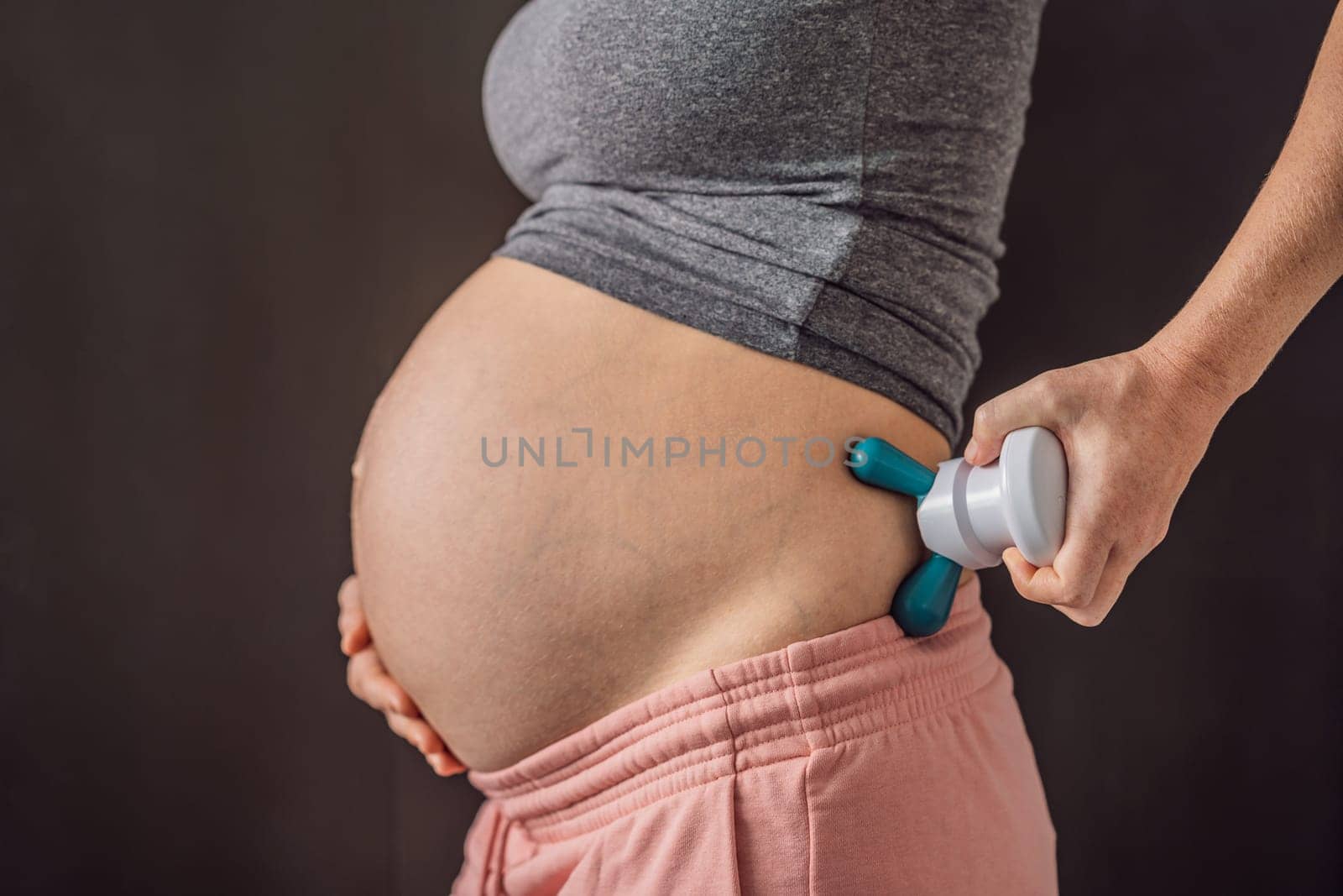 Self-massage with a massager for a pregnant woman.