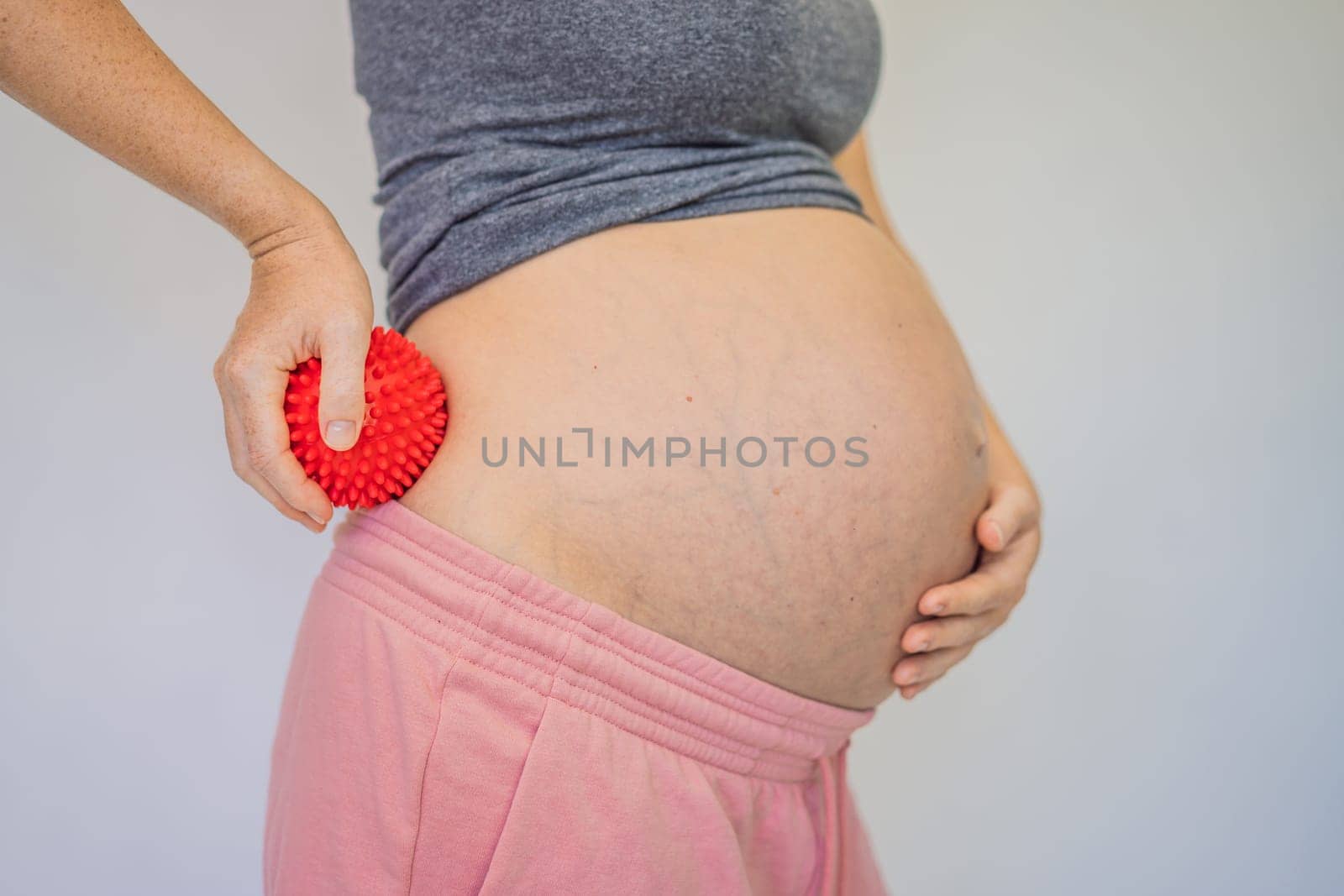 Self-massage with a massager for a pregnant woman.