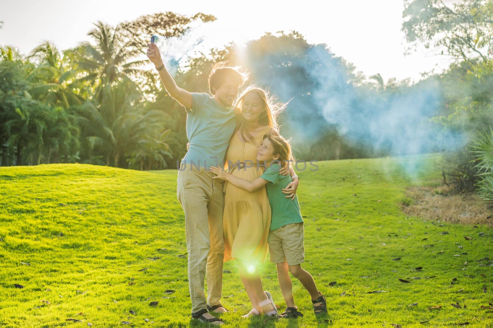 Pregnant mom, dad and son at the gender party on the golf course release blue smoke. Gender reveal announcement on the golf course. Loving family expecting baby boy. Happy moments by galitskaya