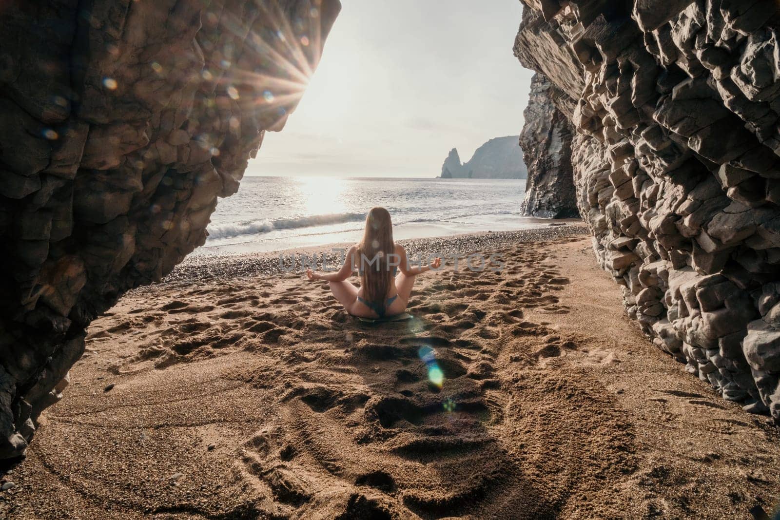 Middle aged well looking woman with black hair doing Pilates with the ring on the yoga mat near the sea on the pebble beach. Female fitness yoga concept. Healthy lifestyle, harmony and meditation.