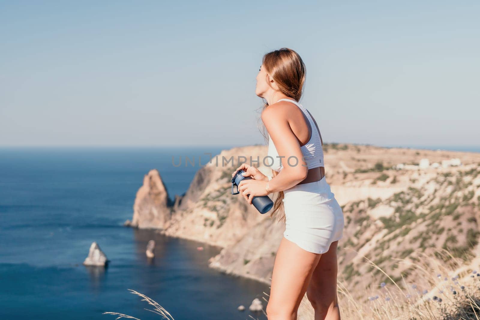 Woman travel sea. Young Happy woman in a long red dress posing on a beach near the sea on background of volcanic rocks, like in Iceland, sharing travel adventure journey