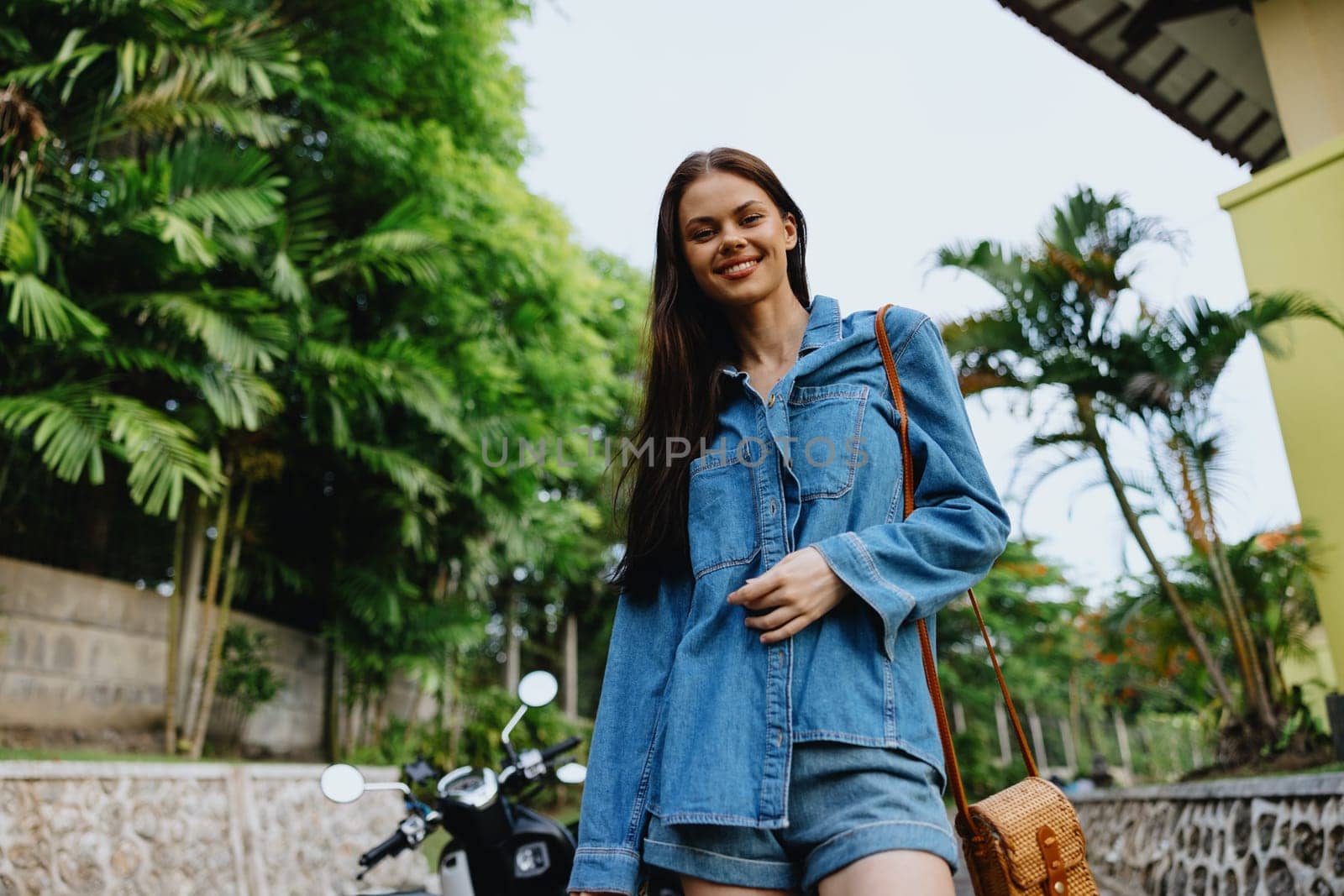 Portrait of a woman brunette smile with teeth running down the street against a backdrop of palm trees in the tropics, summer vacations and outdoor recreation, the carefree lifestyle of a freelance student. High quality photo