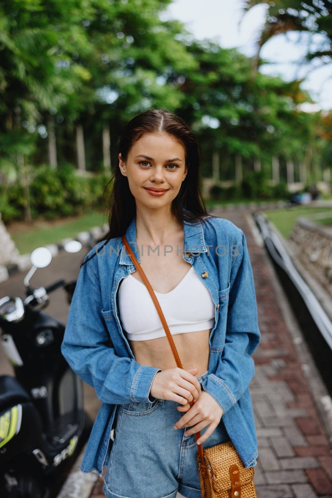 Portrait of a woman brunette smile with teeth walking outside against a backdrop of palm trees in the tropics, summer vacations and outdoor recreation, the carefree lifestyle of a freelance student. by SHOTPRIME