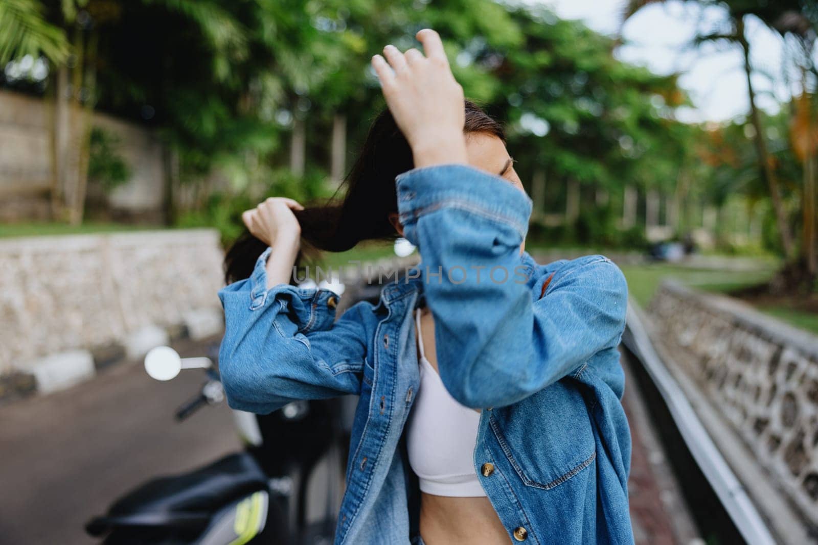 Portrait of a woman brunette smile with teeth walking outside against a backdrop of palm trees in the tropics, summer vacations and outdoor recreation, the carefree lifestyle of a freelance student. High quality photo