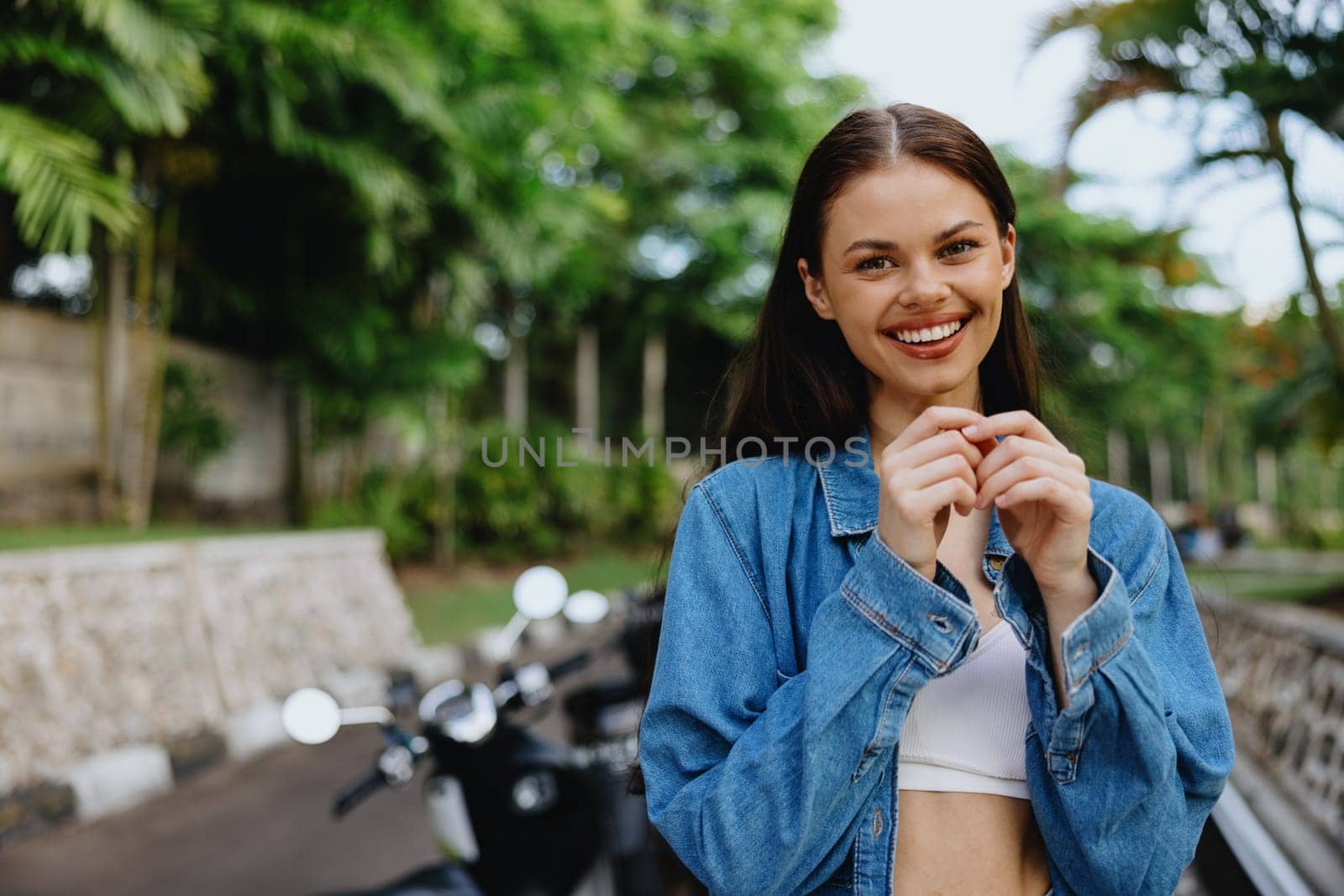 Portrait of a woman brunette smile with teeth walking outside against a backdrop of palm trees in the tropics, summer vacations and outdoor recreation, the carefree lifestyle of a freelance student. High quality photo