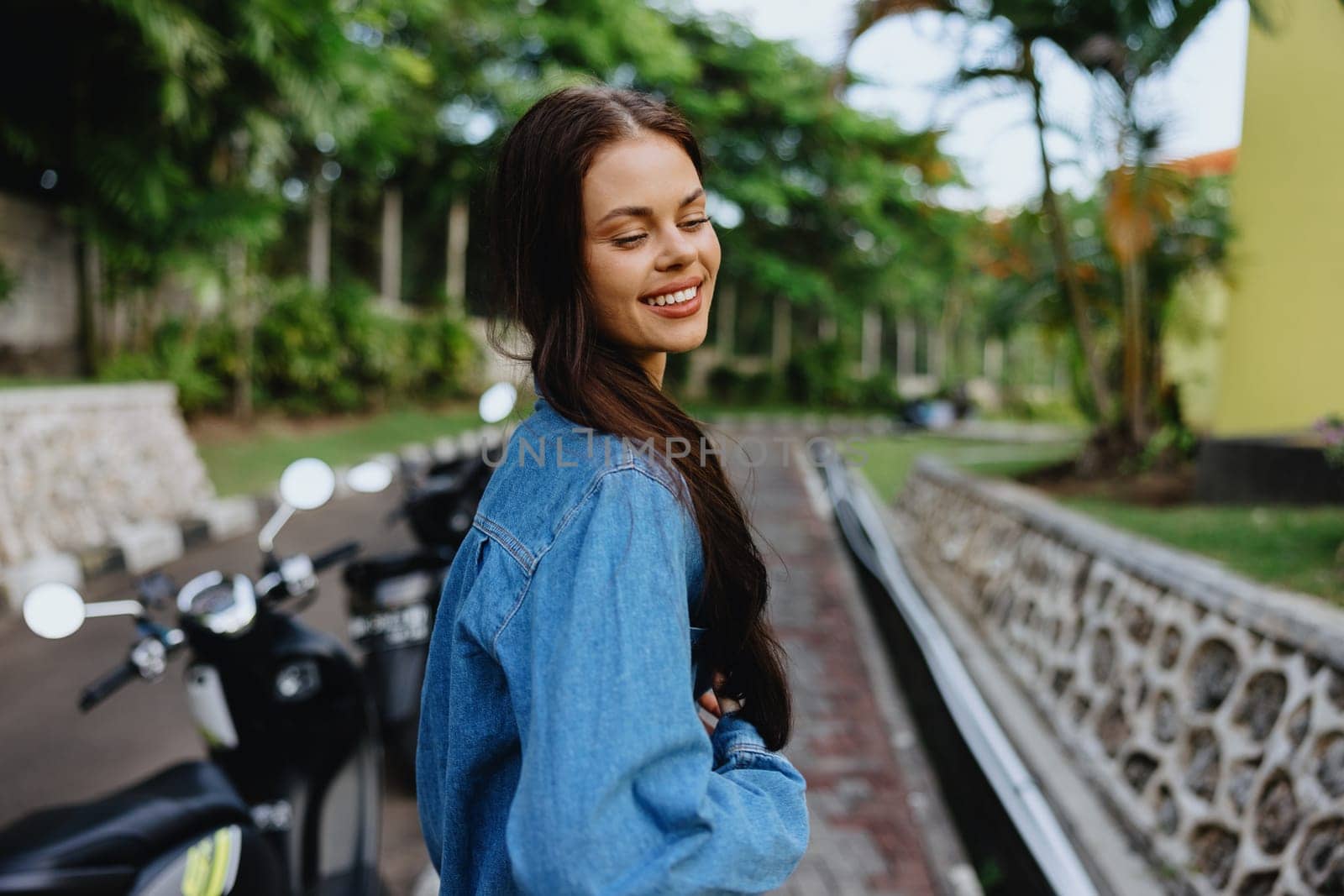 Portrait of a woman brunette smile with teeth walking outside against a backdrop of palm trees in the tropics, summer vacations and outdoor recreation, the carefree lifestyle of a freelance student. High quality photo