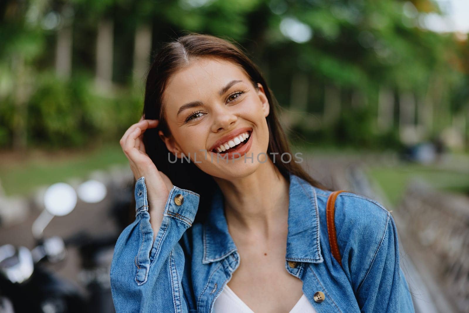 Portrait of a woman brunette smile with teeth walking outside against a backdrop of palm trees in the tropics, summer vacations and outdoor recreation, the carefree lifestyle of a freelance student. High quality photo