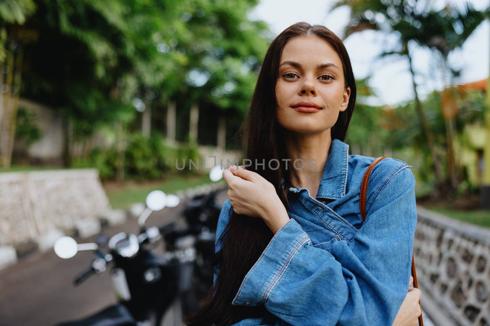 Portrait of a woman brunette smile with teeth walking outside against a backdrop of palm trees in the tropics, summer vacations and outdoor recreation, the carefree lifestyle of a freelance student. High quality photo