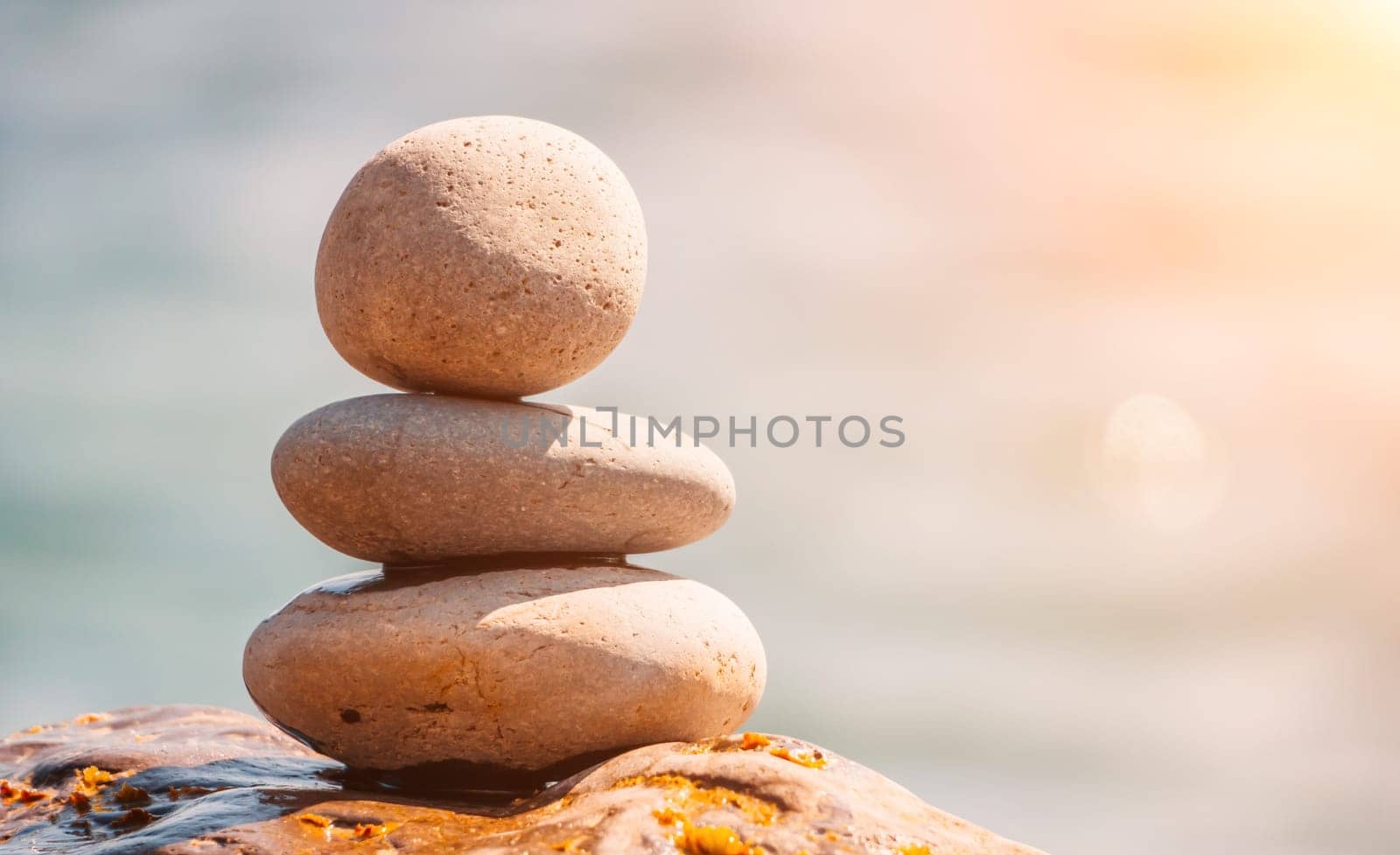 Pyramid stones on the seashore with warm sunset on the sea background. Happy holidays. Pebble beach, calm sea, travel destination. Concept of happy vacation on the sea, meditation, spa, calmness.