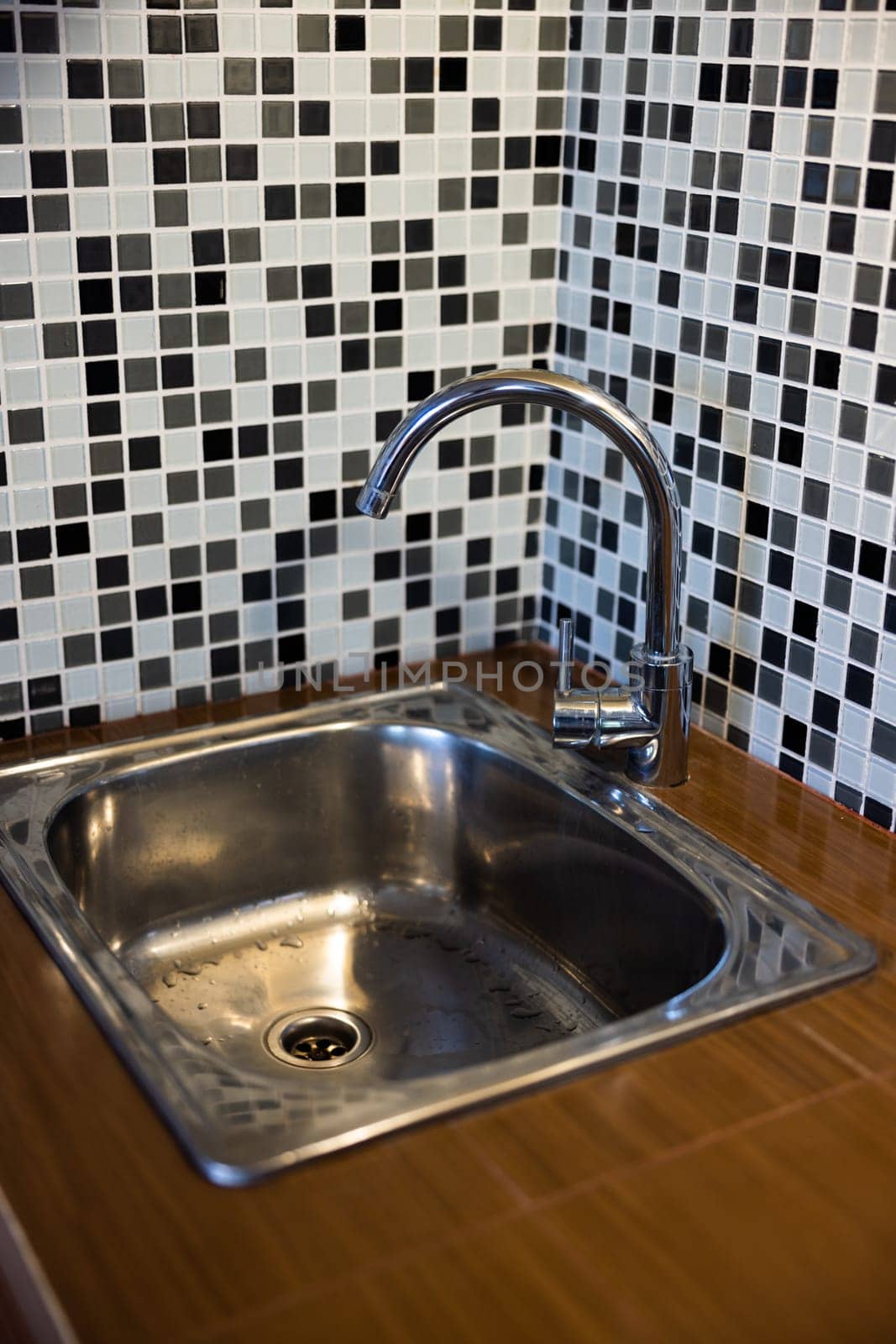 Clean sink with pouring water in the kitchen, metal faucet and sink in an old home interior. High quality photo